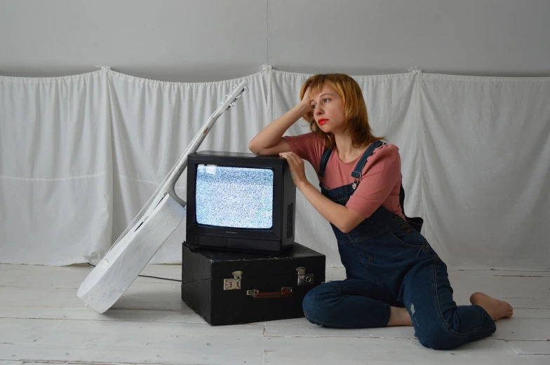 a woman sitting on the floor in front of a television, inspired by Leila Faithfull, artist wearing torn overalls, crt tv mounted, catalog photo, cinematic outfit photo