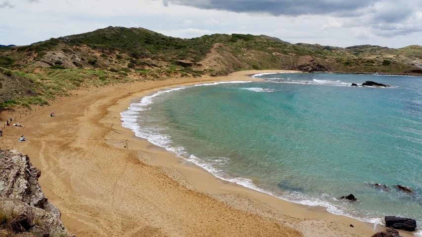 a sandy beach next to the ocean on a cloudy day, renaissance, mediterranean island scenery, múseca illil, sparkling cove, above view