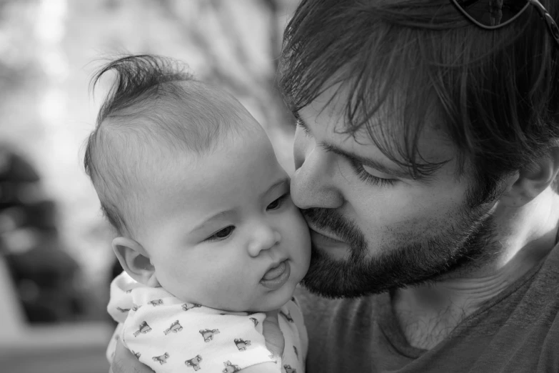 a black and white photo of a man kissing a baby, by Sven Erixson, pexels, beard stubble, square, serious faces, rick dai