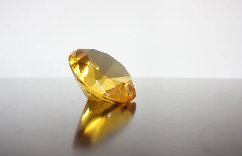 a yellow diamond sitting on top of a table, a picture, pixabay, minimalism, amber jewels, from side, shot on sony alpha dslr-a300, round