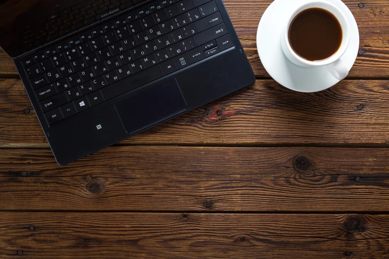 a cup of coffee next to a laptop on a wooden table, a portrait, by Carey Morris, pixabay, wood texture on top, background image, black, bottom angle