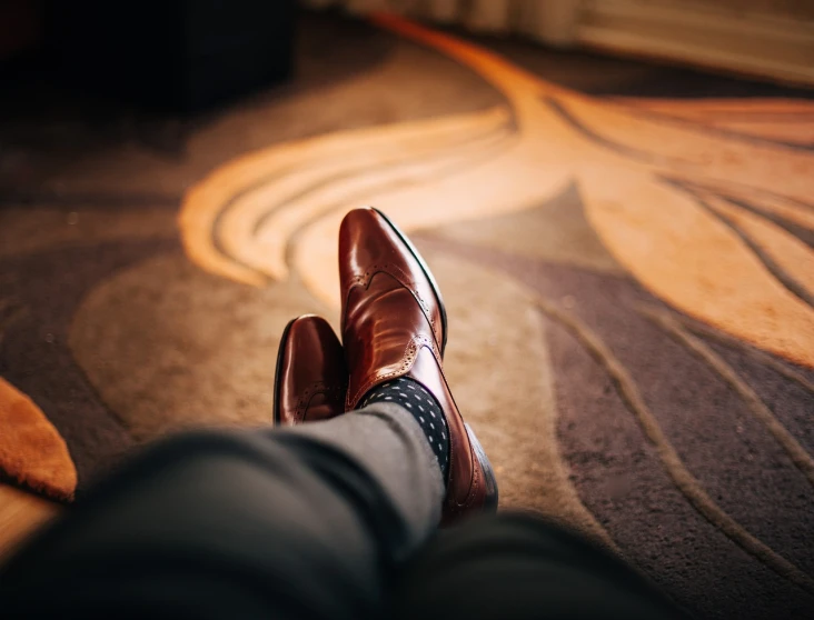 a pair of brown shoes sitting on top of a carpet, by Matthias Weischer, pexels, subject detail: wearing a suit, leather clothing, glowing, istock