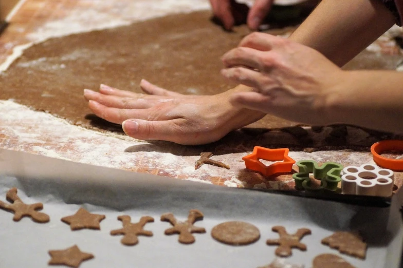 a close up of a person making cookies on a table, inspired by Judy Takács, hand controlling, holiday, an artistic pose, claymotion