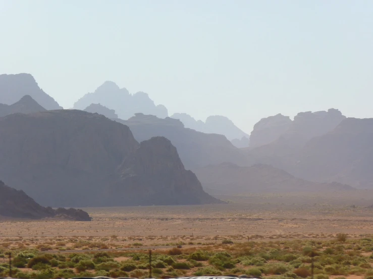 a train traveling through a desert with mountains in the background, by Alexander Johnston, flickr, tonalism, wadi rum, landscape from a car window, (smoke), minarets