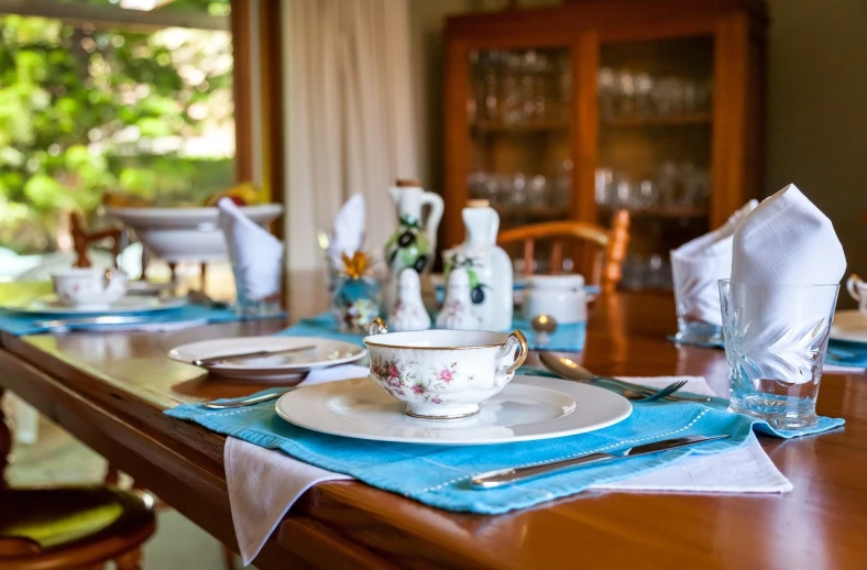 a wooden table topped with plates and silverware, by Alexander Bogen, flickr, blue themed, tea, dining room, colombian