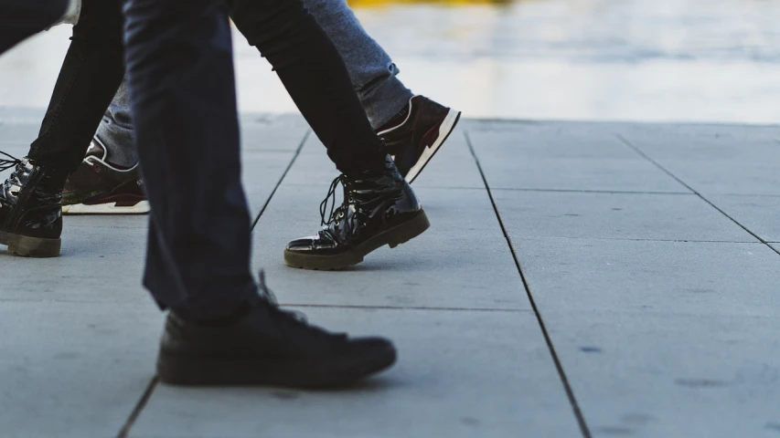 a couple of people walking down a sidewalk, by Niko Henrichon, unsplash, realism, black leather boots, making love, two male, higher details