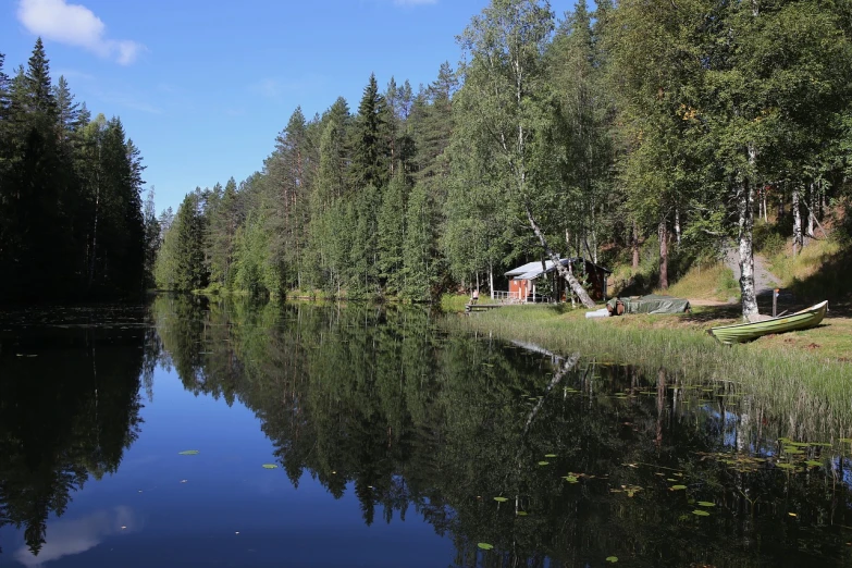 a boat sitting on top of a lake next to a forest, by Eero Järnefelt, shutterstock, small cottage in the foreground, reflections. shady, stock photo, highly detailed picture