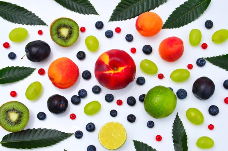 a variety of fruits are arranged on a white surface, cannabis leaves, mdma, productphoto, amazing wallpaper