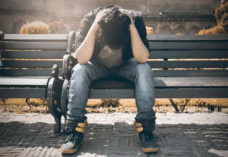 a man sitting on a bench with his head in his hands, a picture, shutterstock, teenage grunge punk rock, stock photo, clinically depressed, asian man