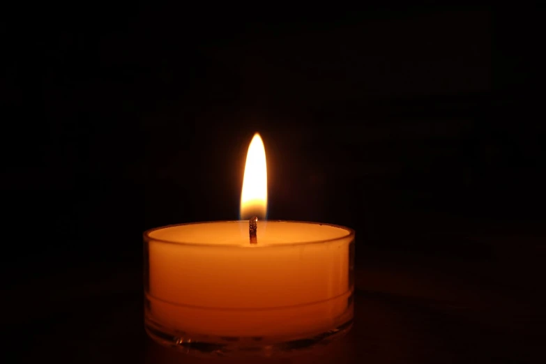 a lit candle sitting on top of a table, by Niko Henrichon, where being rest in peace, istockphoto, night time low light, stock photo