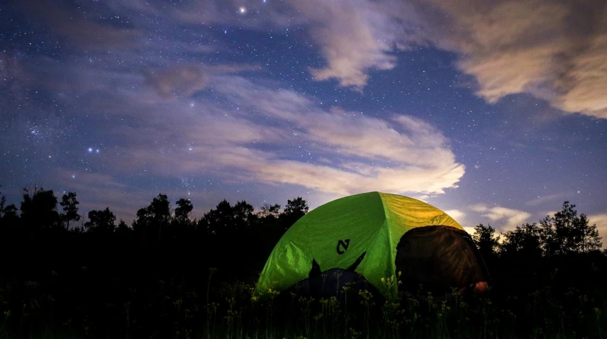 a green tent sitting on top of a lush green field, by Andrew Domachowski, cloudy night sky, campsites, photograph credit: ap, gopro photo