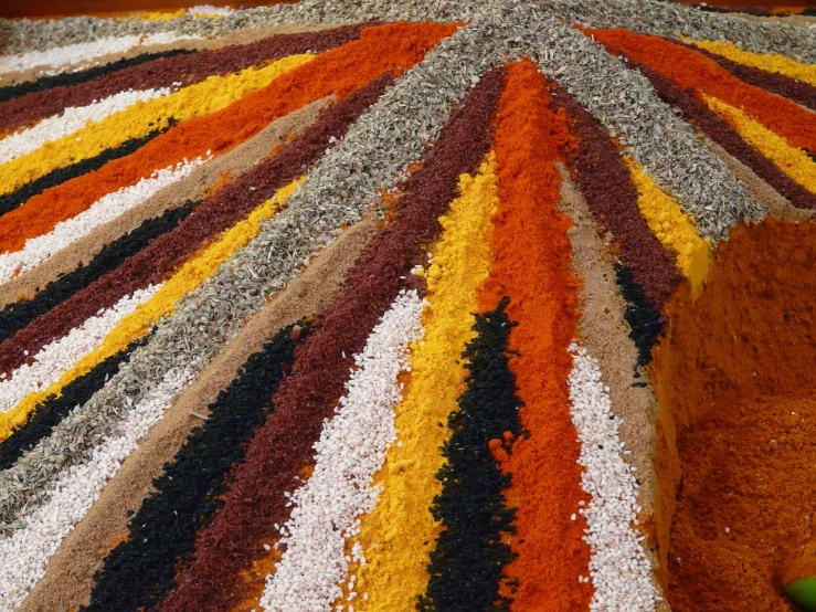a multicolored rug sitting on top of a wooden floor, by Karel Štěch, land art, spices, ocher, closeup at the food, terrazzo