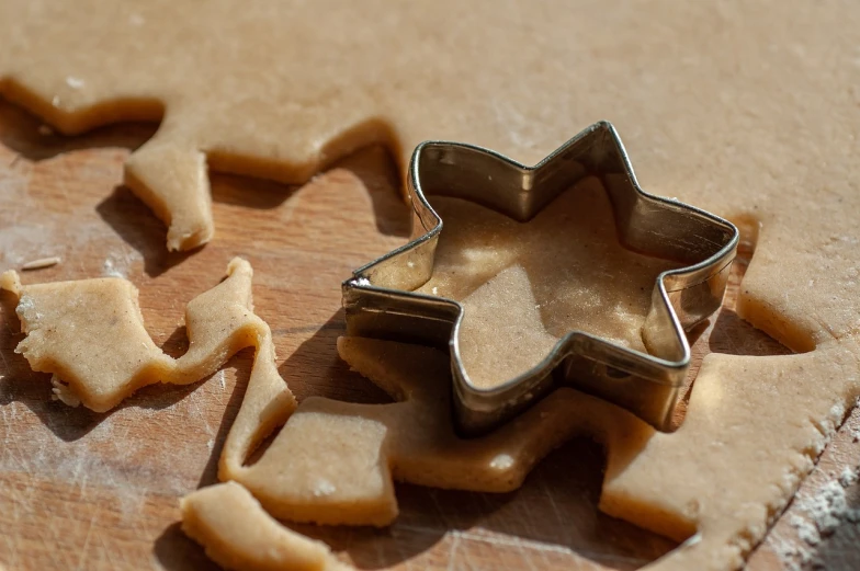 a cookie cutter sitting on top of a wooden cutting board, pexels, folk art, starburst, shiny skin”, eating, mixing