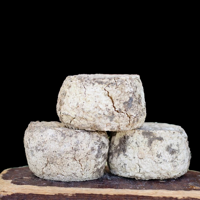 three pieces of cheese stacked on top of each other, by François Girardon, mingei, beautiful aged and rustic finish, tamborine, briclot, in front of a black background