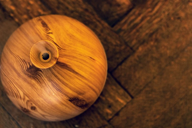 a wooden object sitting on top of a wooden floor, unsplash, hurufiyya, round bottle, gold striated swirling finish, maritime pine, anton semonov