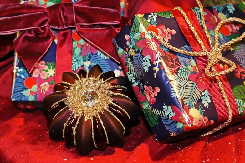 two gift boxes sitting next to each other on a red cloth, sōsaku hanga, floral bling, decorative dark blue clothing, christmas, sandra chevier