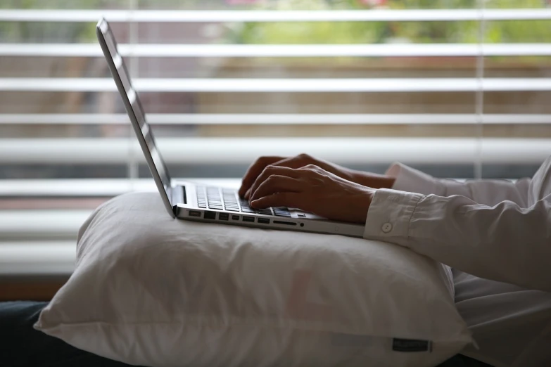 a close up of a person typing on a laptop, figuration libre, resting on a pillow, photograph credit: ap, evening sun, afp