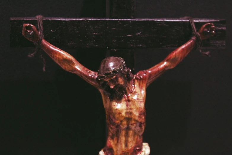 a close up of a statue of jesus on a cross, by Jürg Kreienbühl, hurufiyya, preserved museum piece, blood, 1996, black jesus