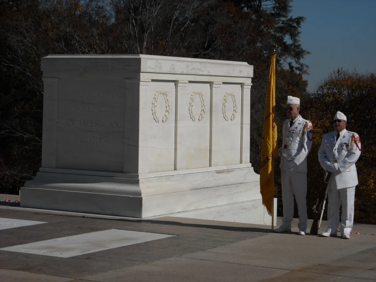 a couple of men standing next to a white monument, by Tom Carapic, flickr, with yellow cloths, white american soldier, tomb, polished white marble