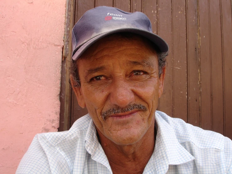 a close up of a person wearing a hat, by Ramón Silva, cuban setting, friendly face, wearing baseball cap, freddy mamani silvestre facade