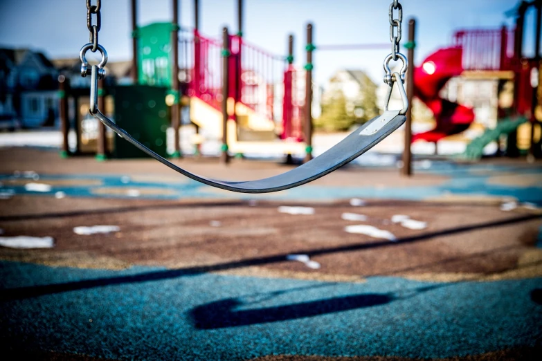 a close up of a swing in a playground, by Niko Henrichon, pexels, bay area, complex background, on the ground, in the center midground