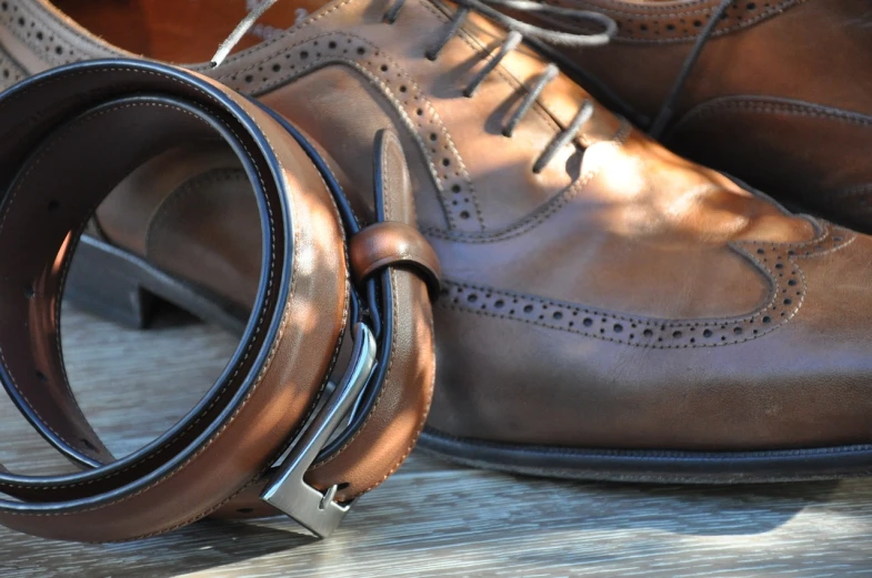 a pair of brown shoes sitting on top of a wooden table, many belts, in the sun, style of alexandre chaudret, finely detailed feature