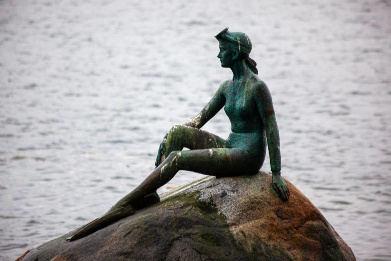 a statue of a woman sitting on top of a rock, a statue, flickr, little mermaid, but very good looking”, green head, captain