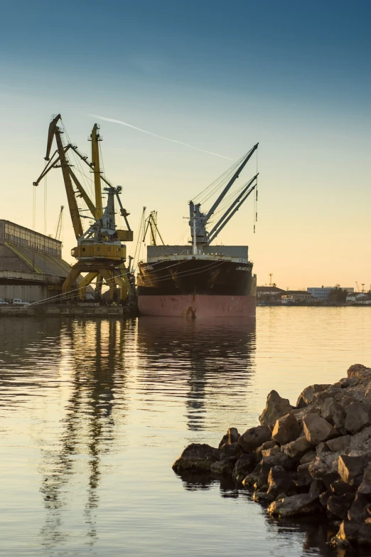 a large boat sitting on top of a body of water, shutterstock, huge machine cranes, peaceful evening harbor, gravel, portlet photo