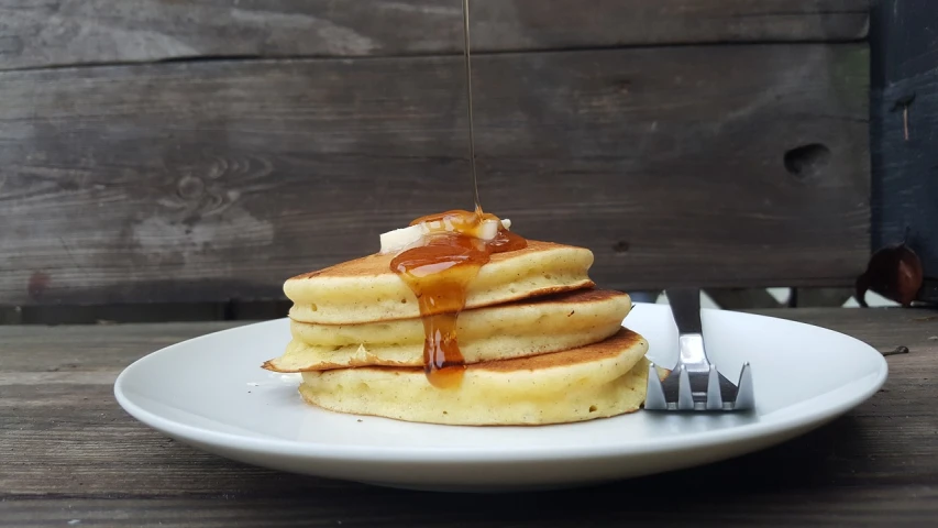 a stack of pancakes sitting on top of a white plate, a portrait, flickr, hurufiyya, maple syrup sea, using fork, melted cheddar, けもの