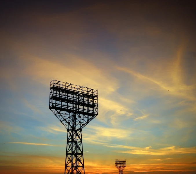 a tall tower sitting in the middle of a field, shutterstock, dramatic stadium lighting, silhouette over sunset, terminal, maintenance photo