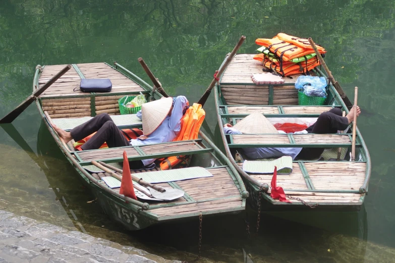 a couple of boats sitting on top of a body of water, a photo, by Richard Carline, vietnamese woman, asleep, random detail, tourist photo