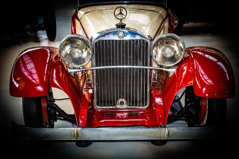 a red car is parked in a garage, by Dave Melvin, pexels, photorealism, golden 1 9 2 0 s, mercedez benz, front light, art deco!!