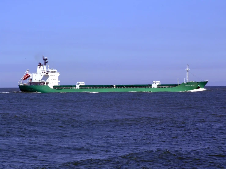 a large green and white boat in the middle of the ocean, by Brad Holland, flickr, utilitarian cargo ship, long tails, large screen, very long