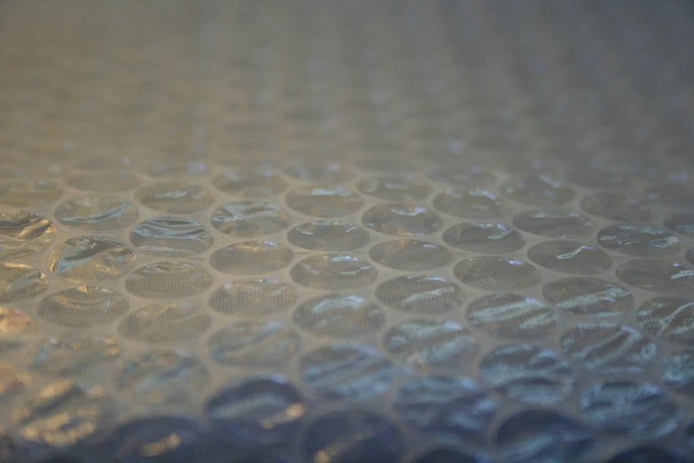 a close up of a piece of glass on a table, a macro photograph, plasticien, honeycomb structure, plastic wrap, fully covered, soft round features