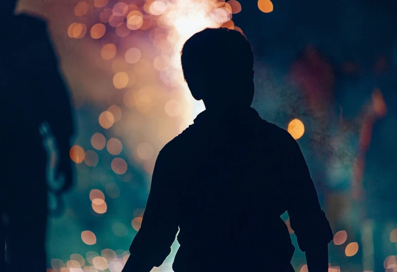 a couple of people that are standing in the dark, by Niko Henrichon, pexels, digital art, bokeh. debadged, light over boy, fireworks, back light contrast