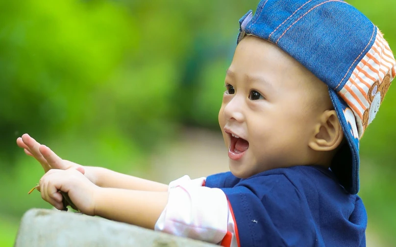 a close up of a child pointing at something, by Basuki Abdullah, smiling playfully, header, crawling towards the camera, wearing a cute hat