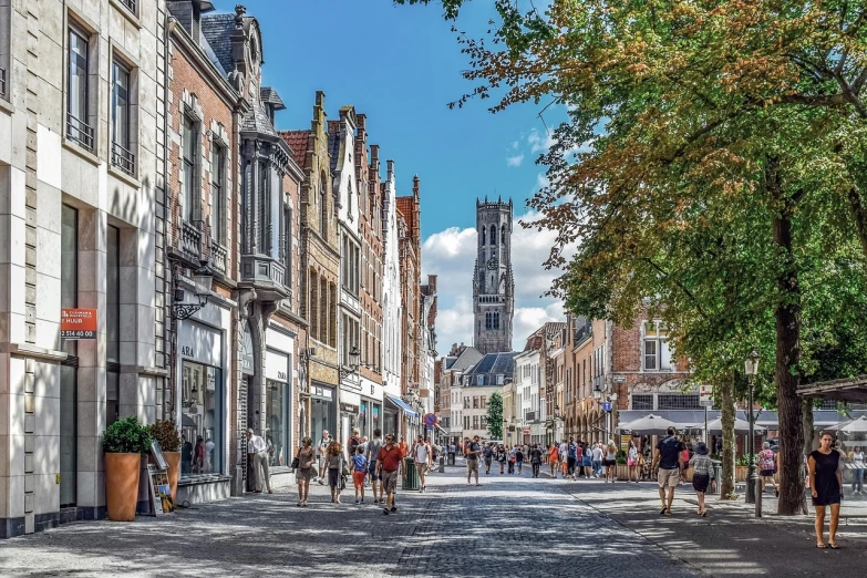 a group of people walking down a street next to tall buildings, by Daniel Seghers, pexels, renaissance, flanders, busy small town street, bright summer day, cathedral in the background