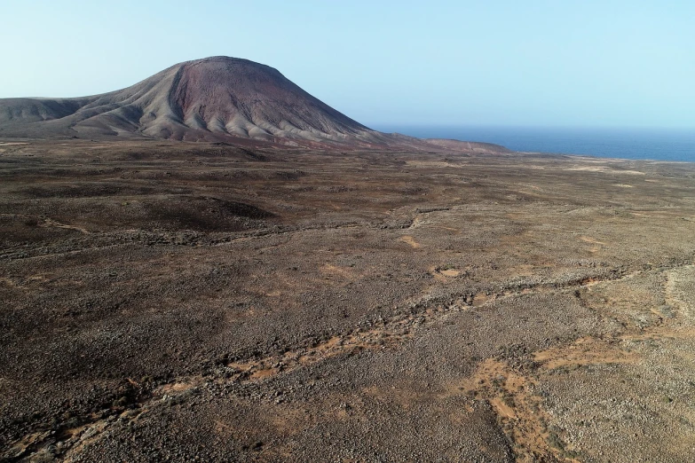 a large mountain in the middle of a desert, by Altichiero, flickr, lava field, uav, múseca illil, island