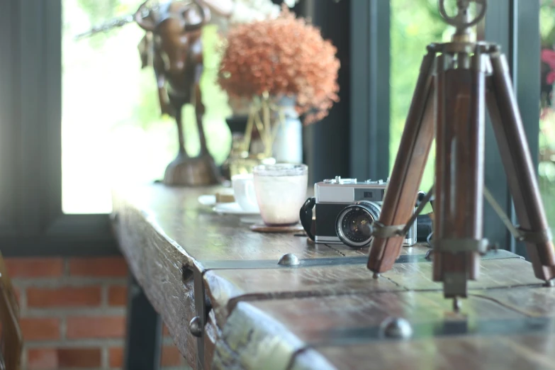 a camera sitting on top of a wooden table, a picture, by Simon Gaon, cafe interior, antique renewal, in style of thawan duchanee, 7 0 mm photo