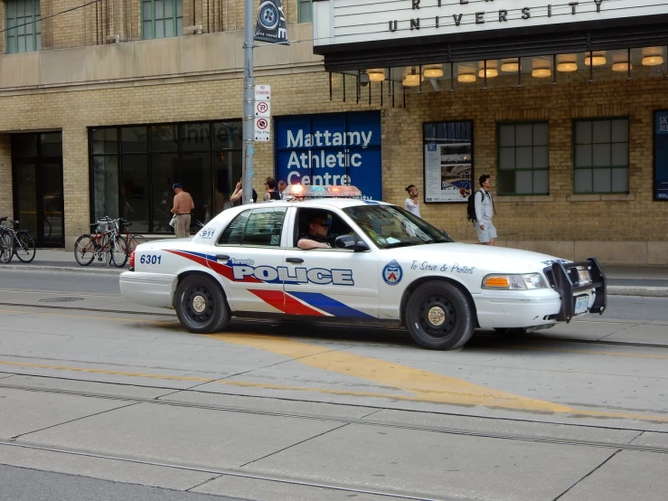 a police car driving down a city street, by Matthew D. Wilson, flickr, dau-al-set, toronto, buff man, platform, white helmet