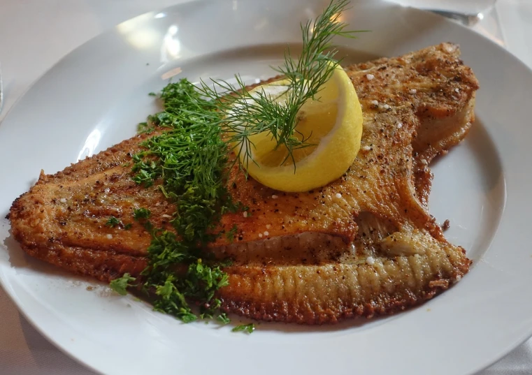 a white plate topped with fish and a lemon, a picture, by Anna Haifisch, 💣 💥, above side view, gills, high grain