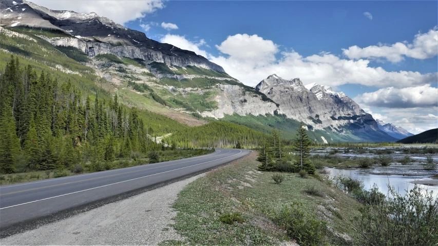 a road that is next to a body of water, by Brigette Barrager, pixabay, bakelite rocky mountains, mountain forest in background, 🚿🗝📝