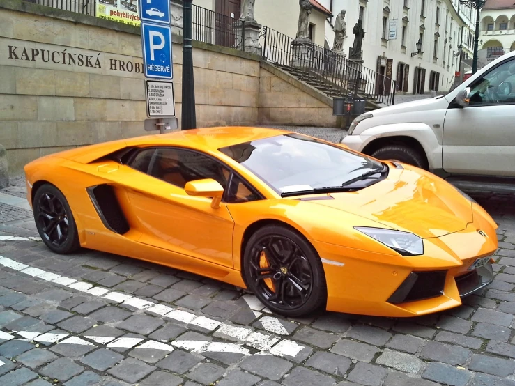 a yellow sports car parked on a cobblestone street, a photo, baroque, lamborghini, dark orange, prague, gold body