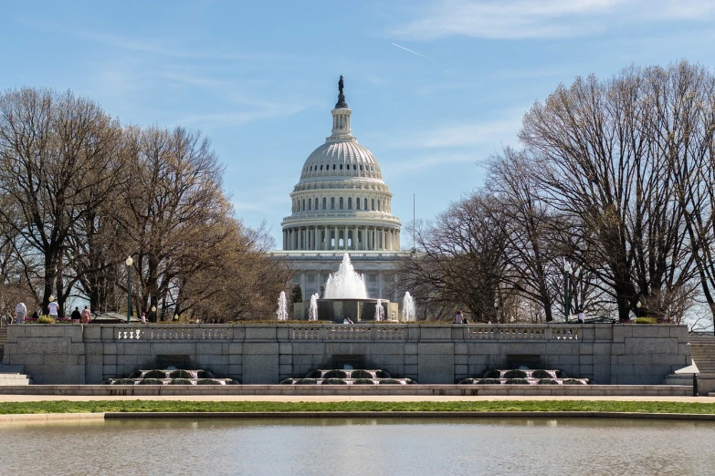 a large building with a fountain in front of it, a picture, by Tom Carapic, shutterstock, capitol hill, riverside, april, monument