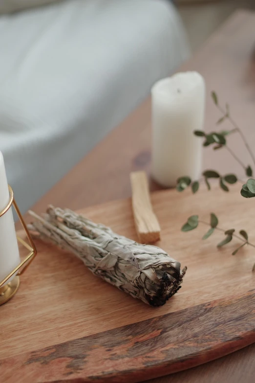 a couple of candles sitting on top of a wooden table, a still life, shutterstock, process art, wearing long white robe, dried plants, high quality product image”