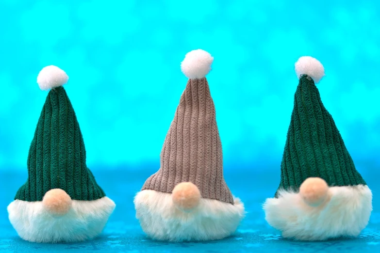 three knitted gnome hats sitting next to each other, a tilt shift photo, figuration libre, wrapped blue background, phone wallpaper hd, green fur, holiday season