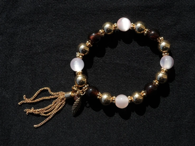 a close up of a bracelet with a tassel, a digital rendering, instagram, ethereal lighting - h 640, brown and gold, rose quartz, exquisite and beautiful