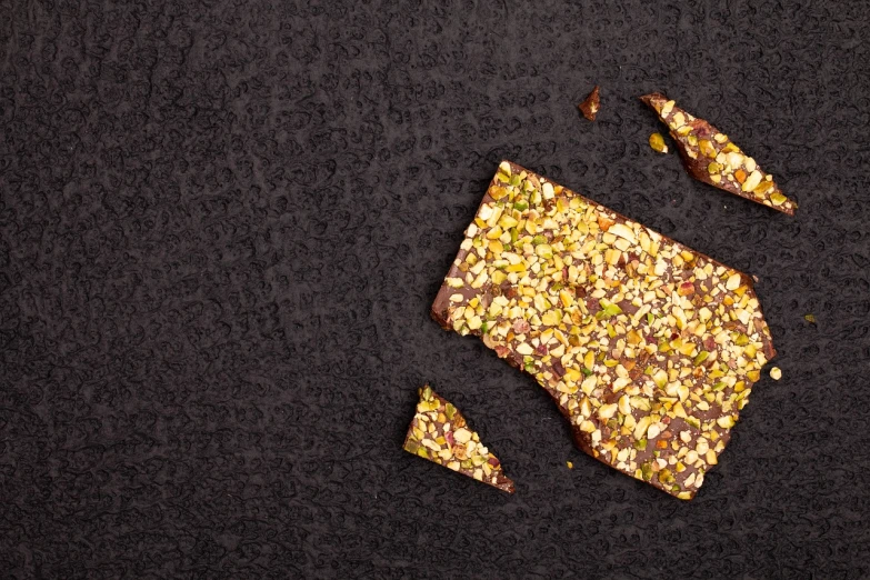 a close up of a piece of food on a table, pexels, arabesque, brittle. highly detailed, on a dark background, high quality product photo, lying scattered across an empty