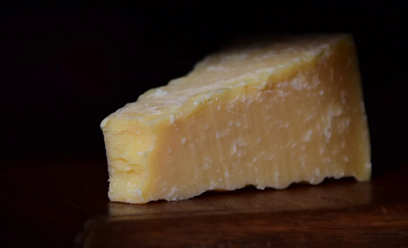a piece of cheese sitting on top of a wooden table, a picture, by Andrew Domachowski, rossdtaws, head and shoulder shot, gwyn, looking from side!