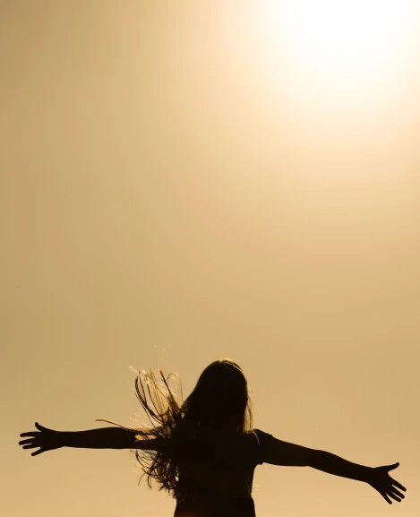 a silhouette of a woman with her arms outstretched in the air, by Max Dauthendey, figuration libre, half image, the sun is shining. photographic, wind in hair, minimalist photo